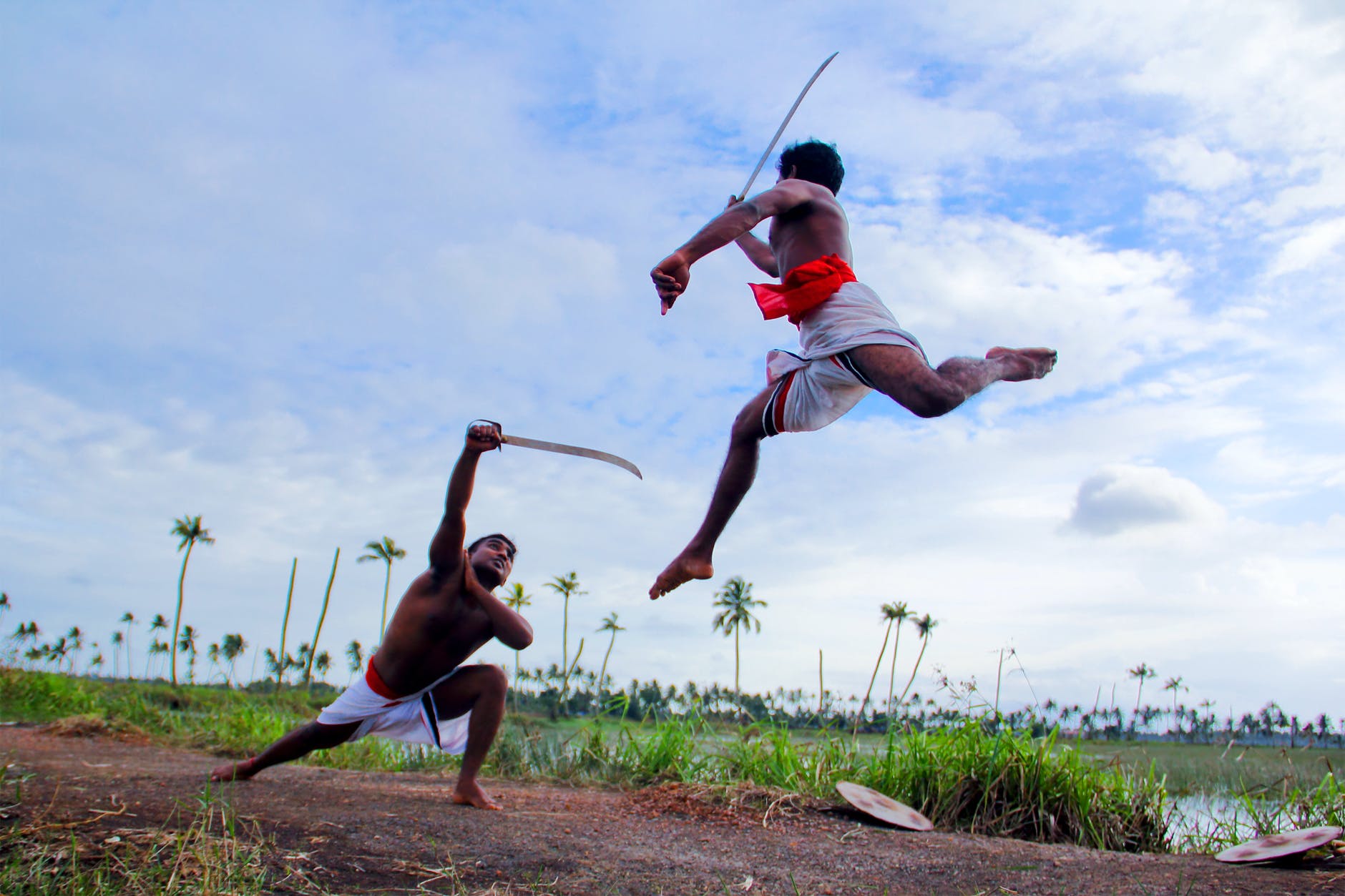 two man in white shorts fighting using sword during daytime